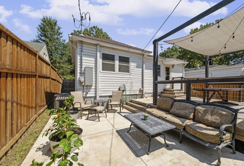 Concrete patio with a wood privacy fence and a shade sail structure