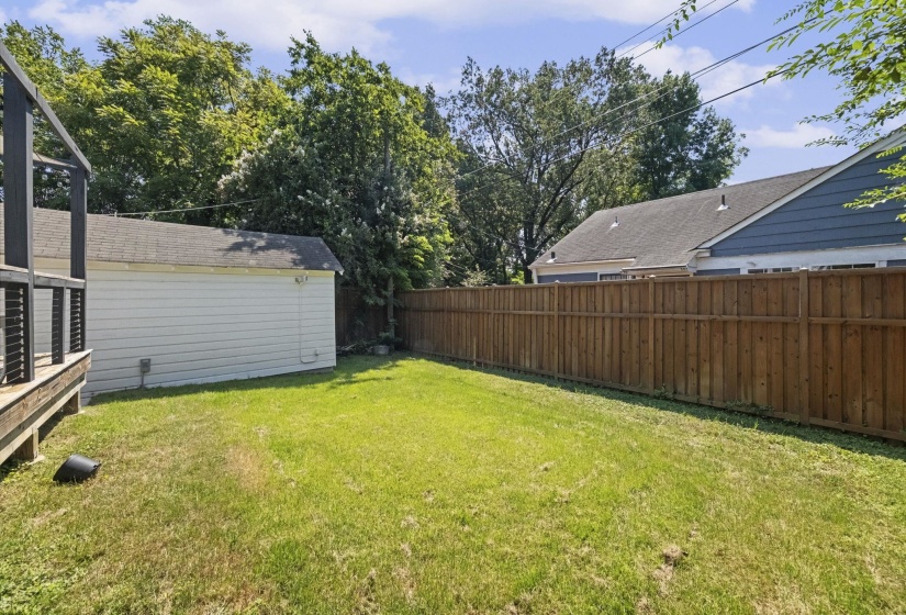 Expansive backyard featuring a natural wood privacy fence, a detached garage, and a wooden deck structure