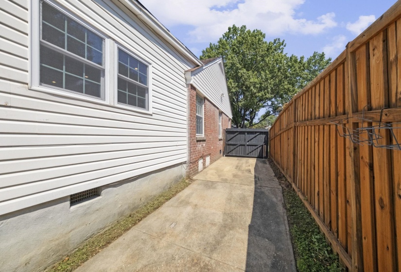 Concrete driveway featuring a privacy fence and a dark-toned gate