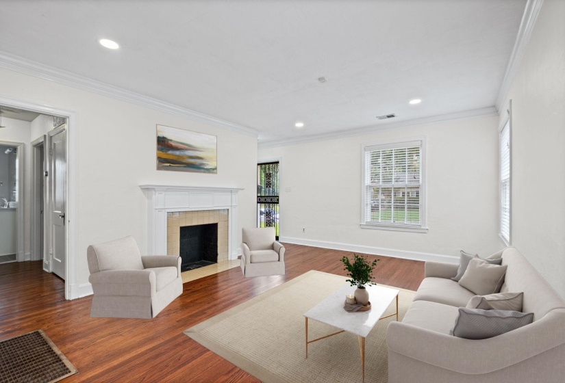 Living area featuring wood-finish flooring, a white mantel fireplace with a light-colored tile surround, recessed lighting, and crown molding