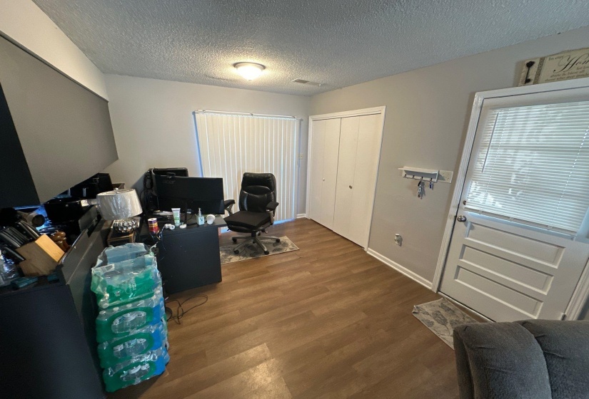 Room featuring wood-finish flooring, neutral wall paint, ceiling-mounted light fixture, and a built-in closet with bifold doors