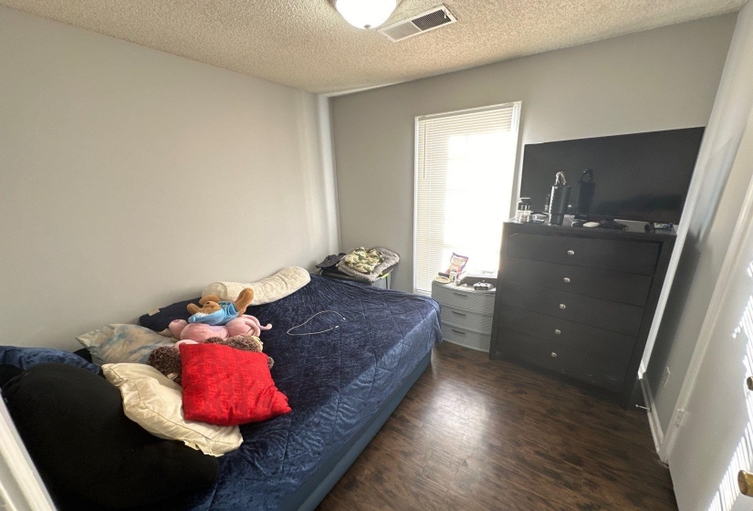Neutral wall paint with wood-finish flooring and a single window featuring horizontal blinds