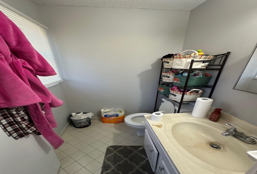 Compact bathroom featuring a single vanity with an integrated sink, a toilet, and light-toned tile flooring