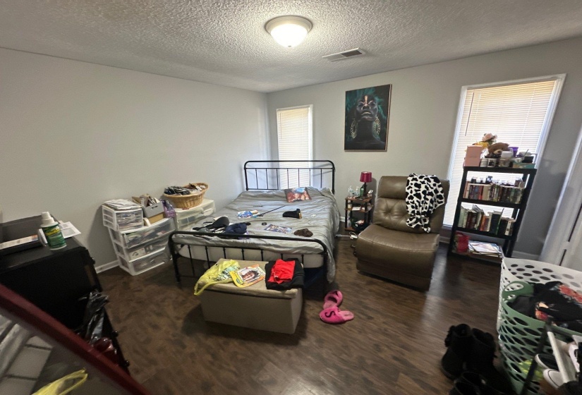 Interior room with wood-finish flooring, light gray wall paint, and a ceiling-mounted light fixture