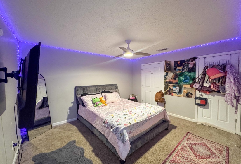 Carpeted room featuring a ceiling fan with integrated lighting, neutral wall paint, and white trim