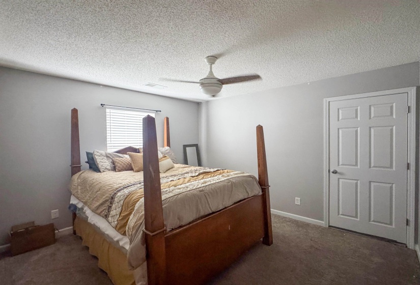 Carpeted room featuring a ceiling fan, window with blinds, and white paneled door