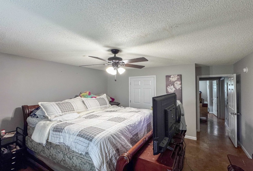 Spacious room featuring neutral painted walls, textured ceilings, a ceiling fan with integrated lighting, and wood-finish flooring