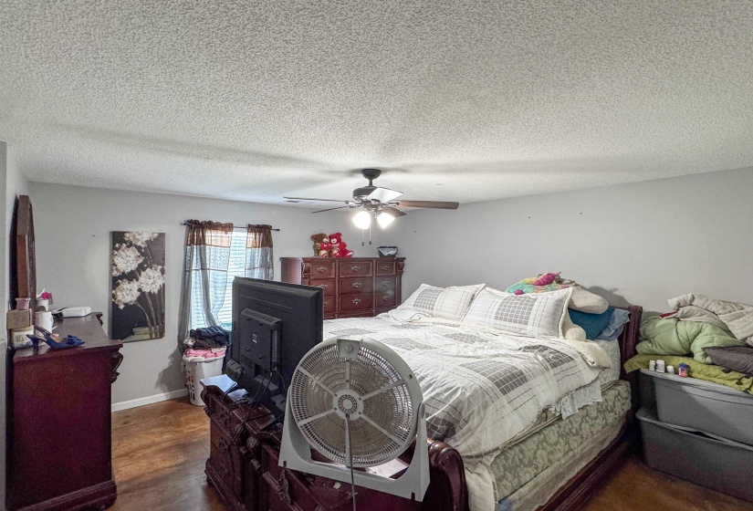Spacious room featuring wood-finish flooring, light grey painted walls, and a ceiling fan with integrated lighting