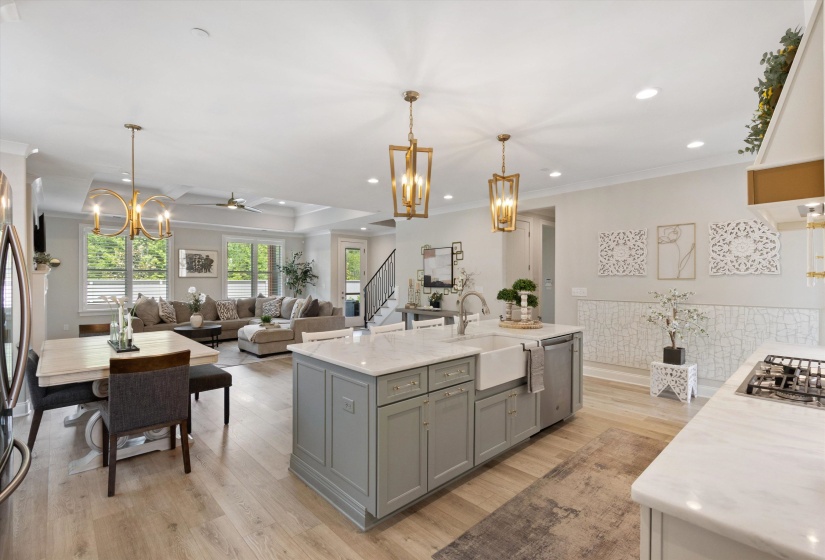 Open-concept kitchen and living area featuring light wood-finish flooring, a kitchen island with a farmhouse sink and light-toned cabinetry, and recessed lighting