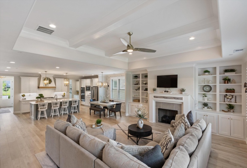 Open-concept living space featuring wood-finish flooring, a tray ceiling with recessed lighting, and a kitchen island with seating