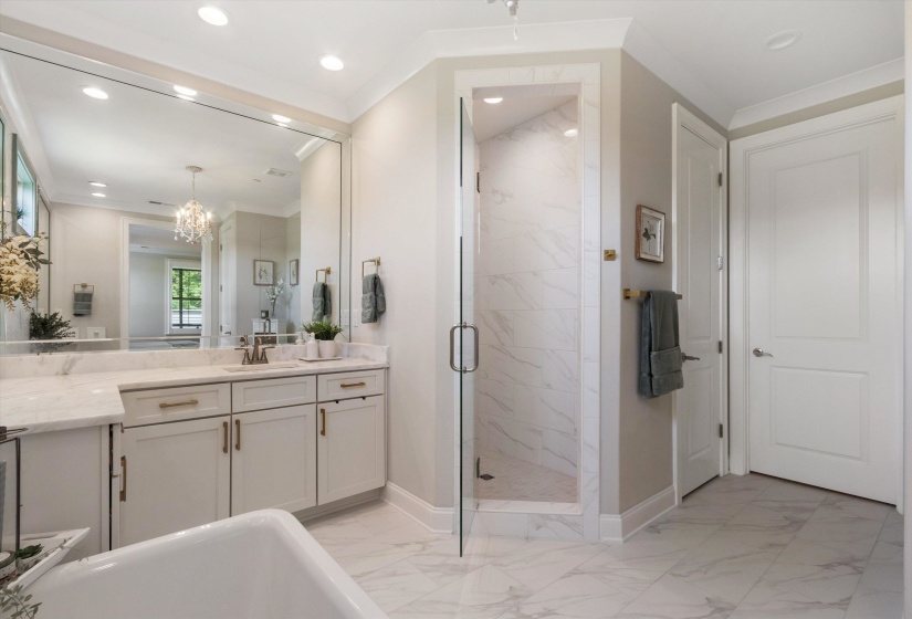 Dual vanity with stone countertops, an integrated glass-enclosed shower, white cabinetry with brass hardware, and large format tile flooring