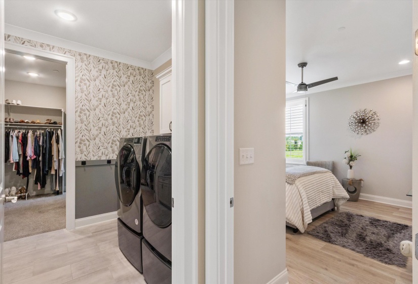 Laundry area featuring patterned wallpaper and light tile flooring, with a walk-in closet beyond