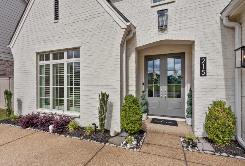 White-painted brick exterior featuring a prominent arched entryway with double gray paneled doors