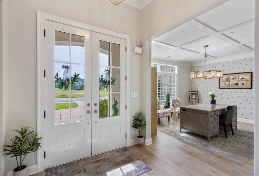Double entry doors with glass panels and sidelights open to an interior with wood-finish flooring