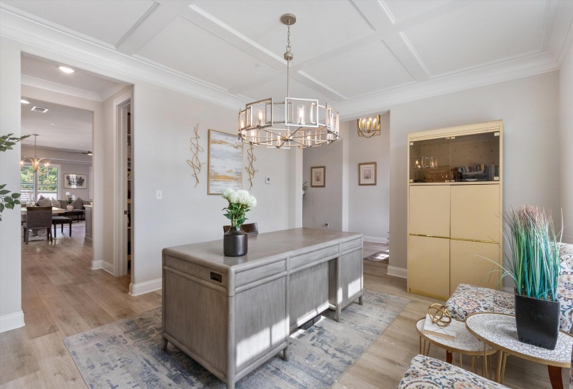 Spacious room featuring wood-finish flooring, a coffered ceiling, and a contemporary chandelier