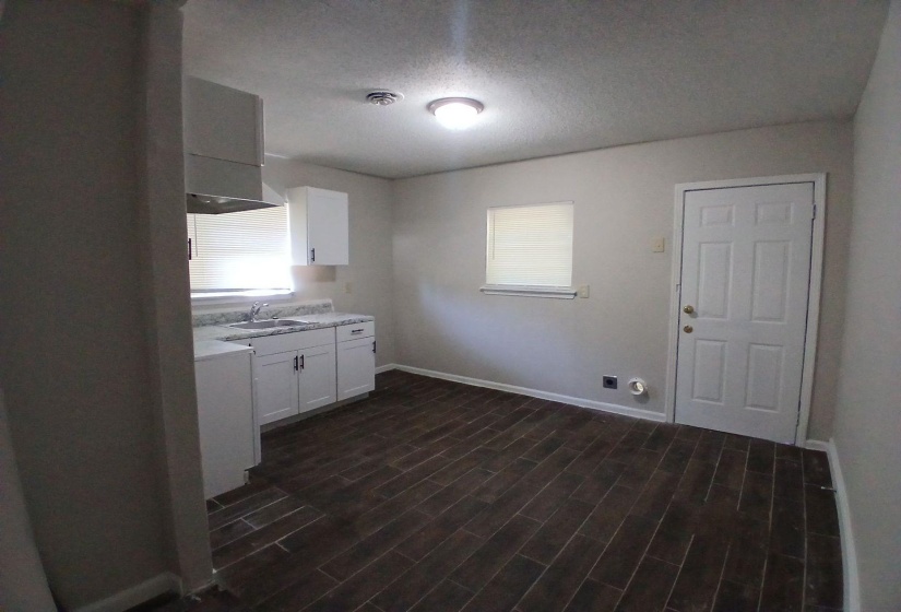 Kitchen space featuring wood-finish flooring, white cabinetry, and light-toned countertops
