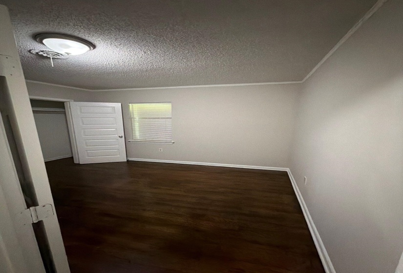 Room featuring wood-finish flooring, light gray walls, white baseboards, and a neutral ceiling