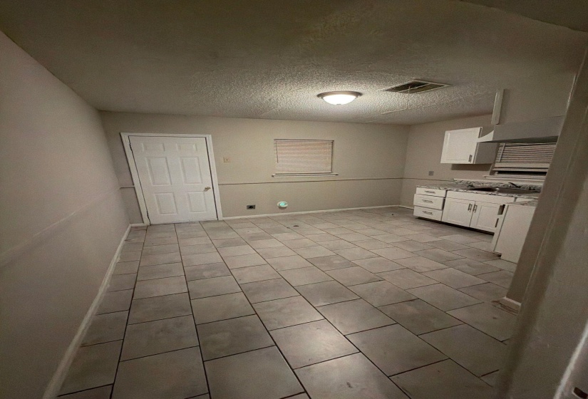 Kitchen area featuring large format tile flooring, white cabinetry, integrated range hood, and a ceiling-mounted light fixture