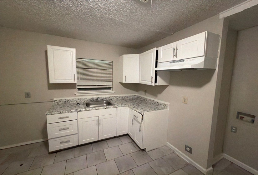 Kitchen featuring white shaker-style cabinetry, granite-patterned countertops, and a stainless steel sink