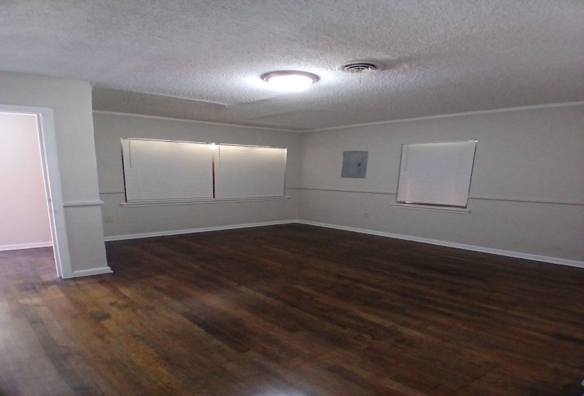 Room featuring wood-finish flooring, white baseboards, and two windows with blinds