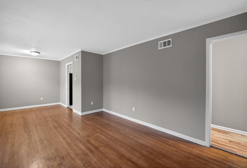 Spare room with ornamental molding and dark wood-type flooring