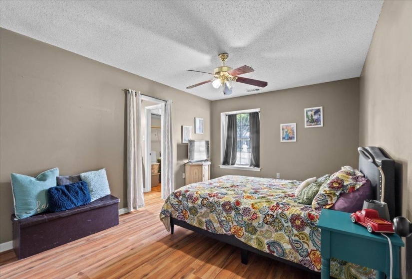 Interior space featuring wood-finish flooring, a ceiling fan with integrated lighting, and a window with dark draperies