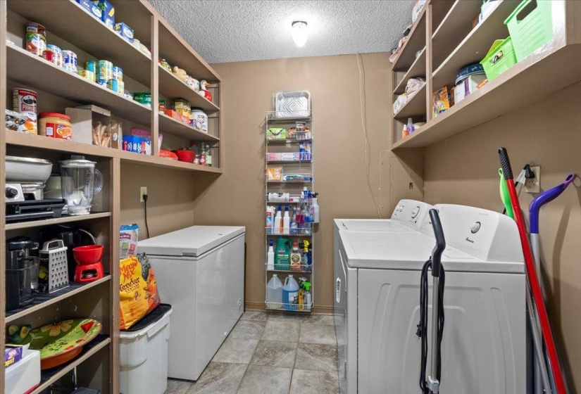 Utility room featuring a top-load washing machine, built-in shelving, a chest freezer, and neutral-toned wall paint
