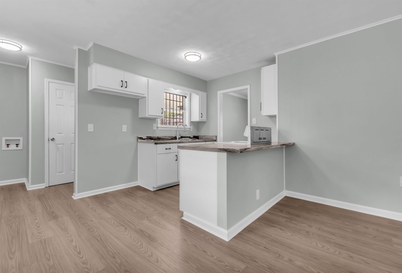 Kitchen featuring white cabinetry, dark countertops, a breakfast bar, wood-finish flooring, and recessed lighting