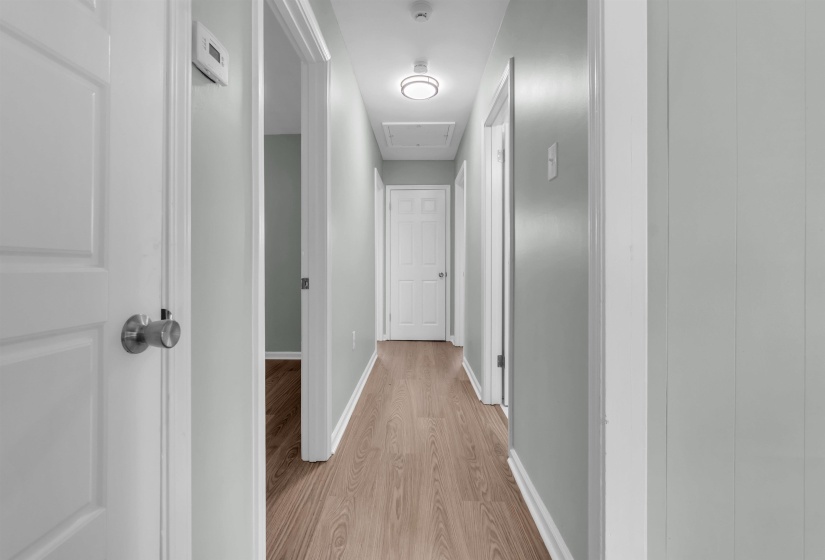 Hallway featuring wood-finish flooring, white doors, and light-toned walls