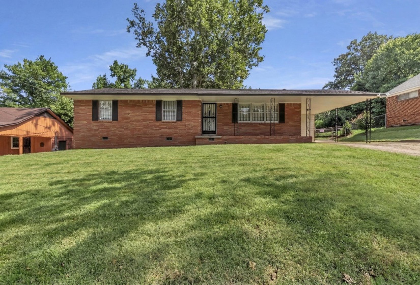Brick ranch-style residence featuring a prominent front lawn