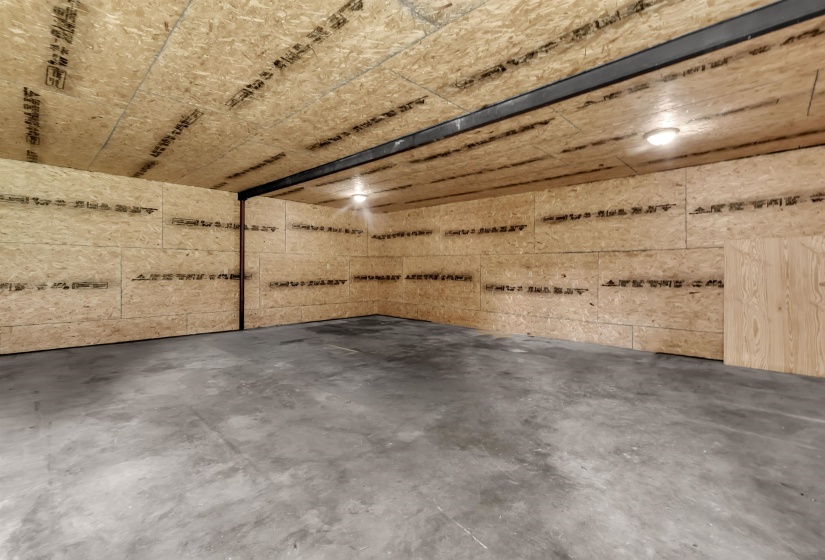 Spacious unfinished interior featuring a concrete floor, OSB panel walls, and an OSB panel ceiling
