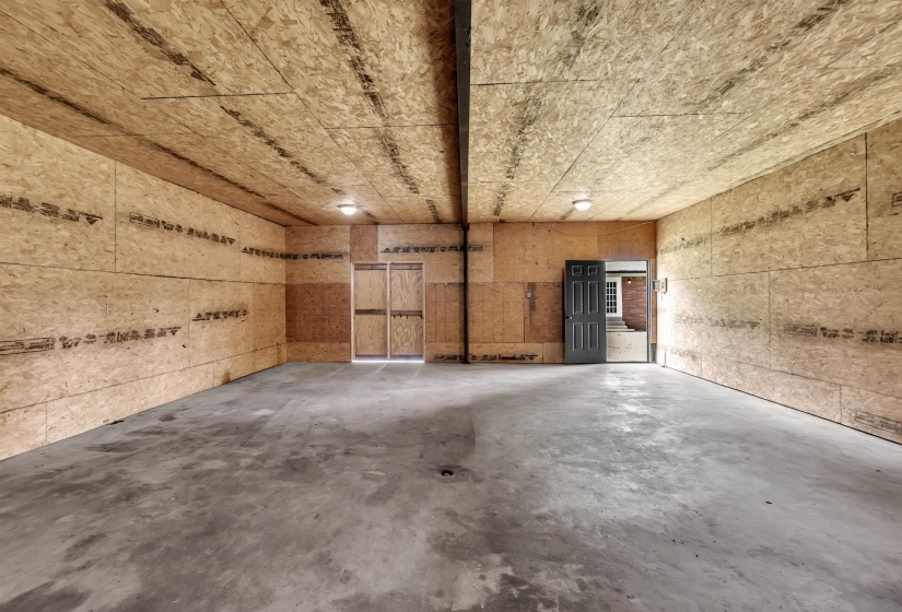 Expansive interior space featuring oriented strand board walls and ceiling, concrete flooring, and multiple entryways