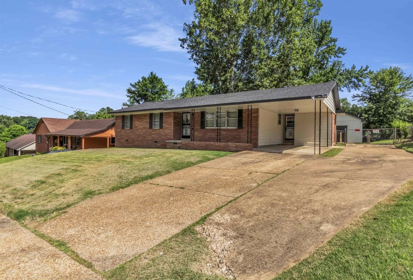 Brick exterior featuring a covered carport and a concrete driveway