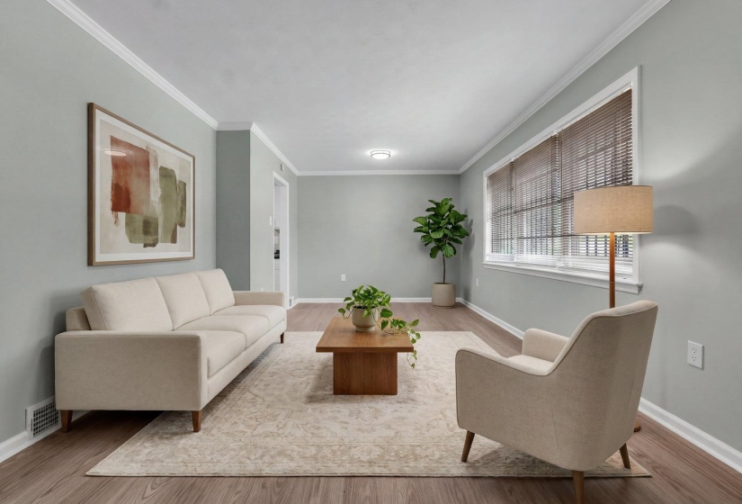 Spacious living area featuring crown molding, wood-finish flooring, and a large window with horizontal blinds