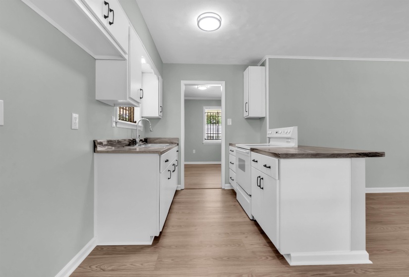 Kitchen featuring white cabinetry, dark countertops, a white electric range, a stainless steel sink with a gooseneck faucet, and wood-finish flooring