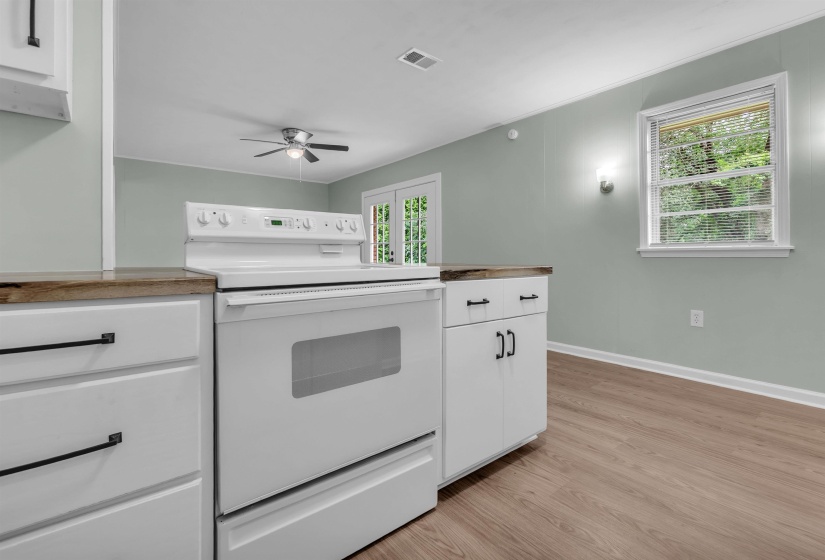 Kitchen area featuring white cabinetry with dark hardware and a white electric range