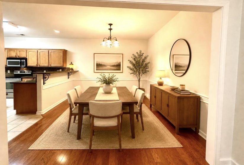 Virtaually staged: Dining area featuring wood-finish flooring, a chandelier fixture, and wainscoting