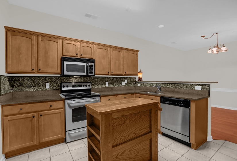 Kitchen featuring wood cabinetry, stainless steel appliances, a mosaic tile backsplash, and a central wood island