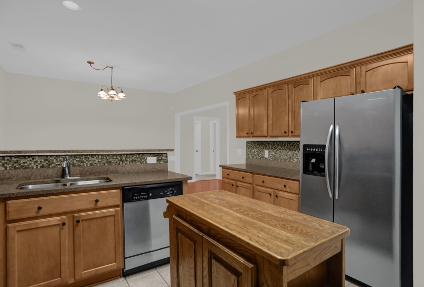Kitchen featuring wood cabinetry, stainless steel appliances, a center island with a wood countertop, a mosaic tile backsplash, and recessed lighting