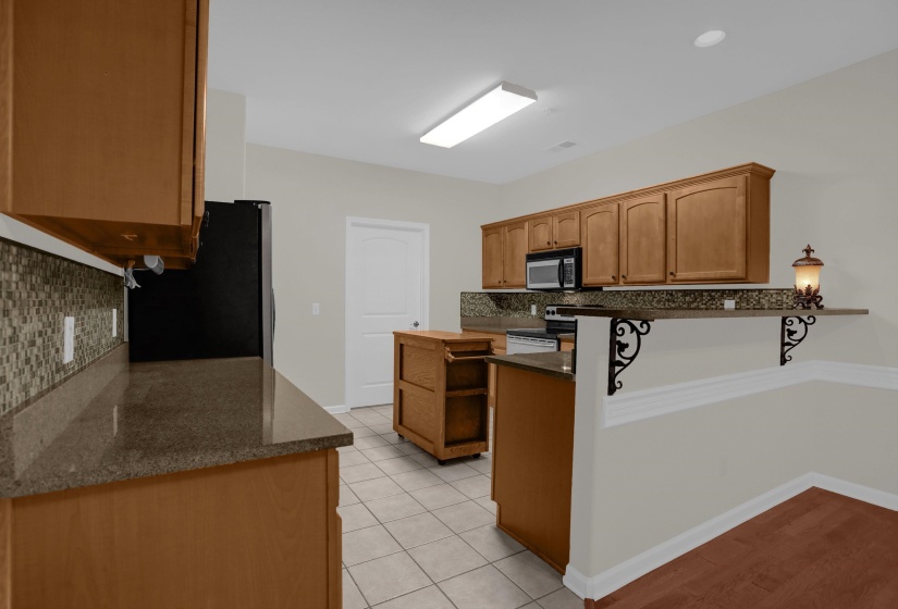 Kitchen featuring wood-finish cabinetry, dark speckled countertops, and a mosaic tile backsplash