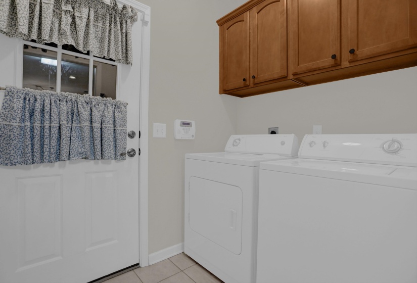 Laundry area with upper wood cabinets, a white door with glass panels, and neutral-toned wall paint