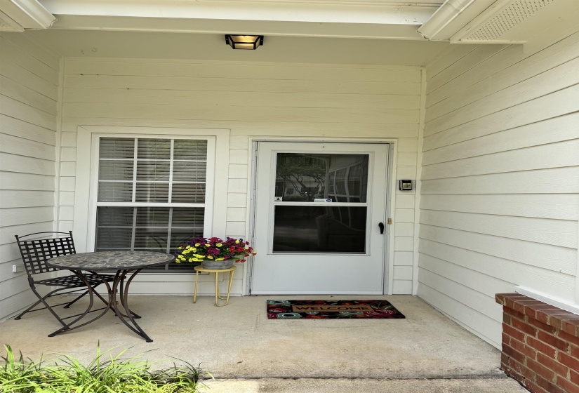 Entryway featuring a white paneled door, an adjacent window with horizontal blinds, and a porch light fixture