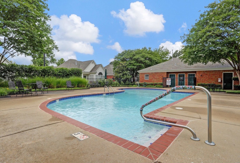 Community swimming pool with a concrete sundeck and brick coping