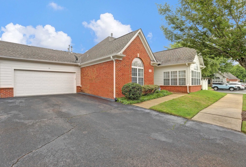 Brick and siding exterior featuring a two-car garage, pitched shingle roof, and an arched window
