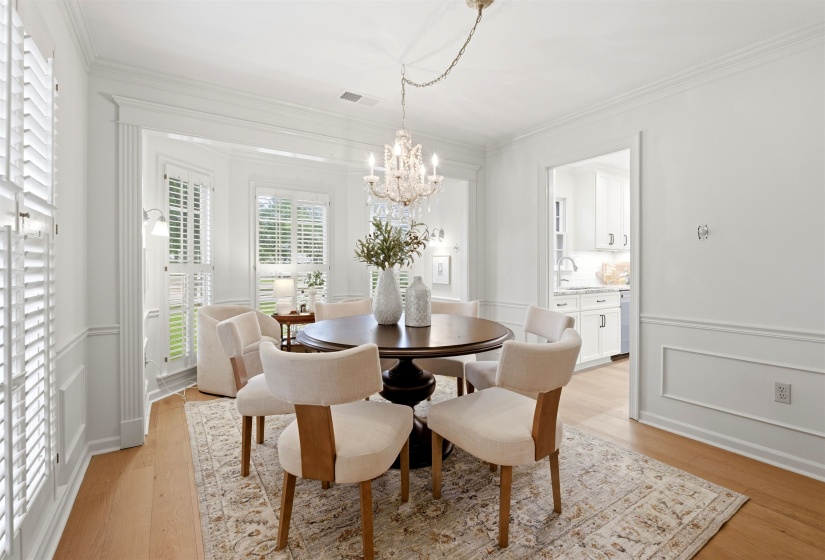 Dining space featuring a crystal chandelier, hardwood flooring, and white plantation shutters