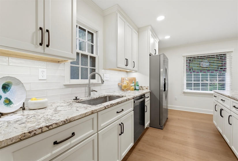 Kitchen featuring white shaker cabinetry, stainless steel appliances, speckled stone countertops, and wood-finish flooring