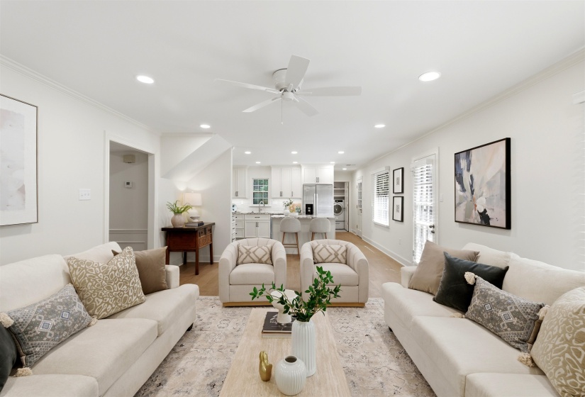 Open-concept living area featuring light wood-finish flooring, recessed lighting, a ceiling fan, and white walls