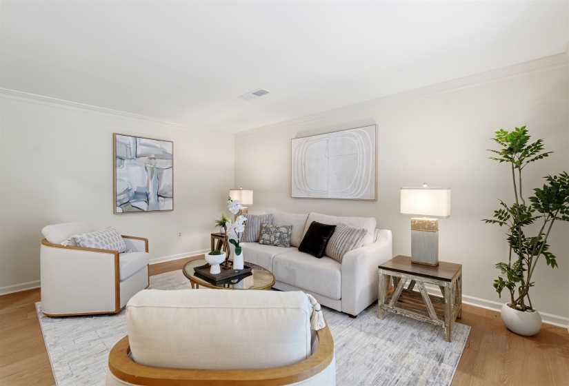 Light-filled living area featuring wood-finish flooring, crisp white walls, and crown molding