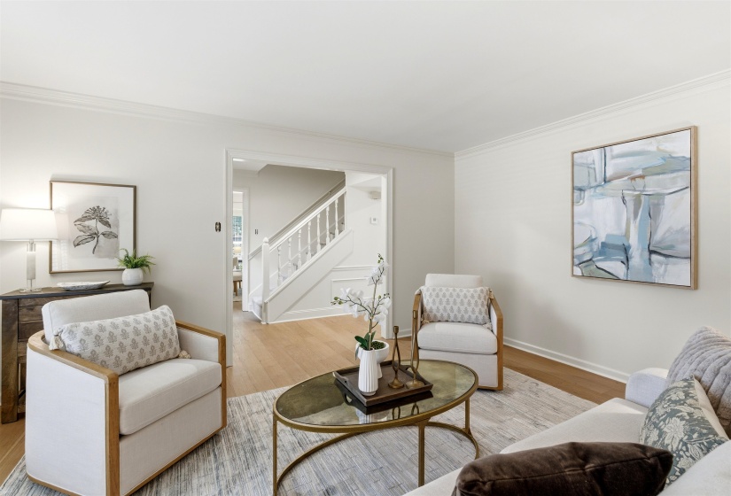 Living area with wood-finish flooring, light-toned wall paint, and crown molding