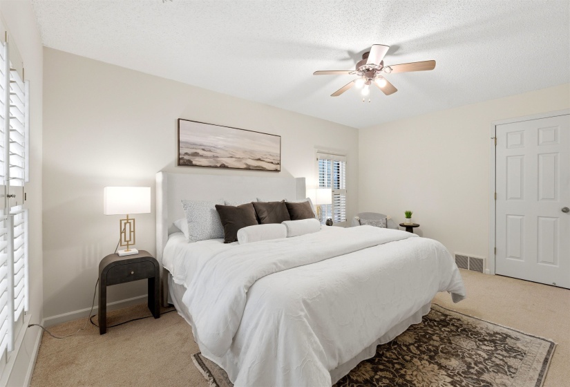 Spacious bedroom featuring light neutral wall tones and plush carpet flooring